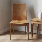 Quadratisches Teaserbild eines hochwertigen massiven Eichenstuhls in moderner, heller Interior-Ecke mit klar sichtbarer Holzmaserung.